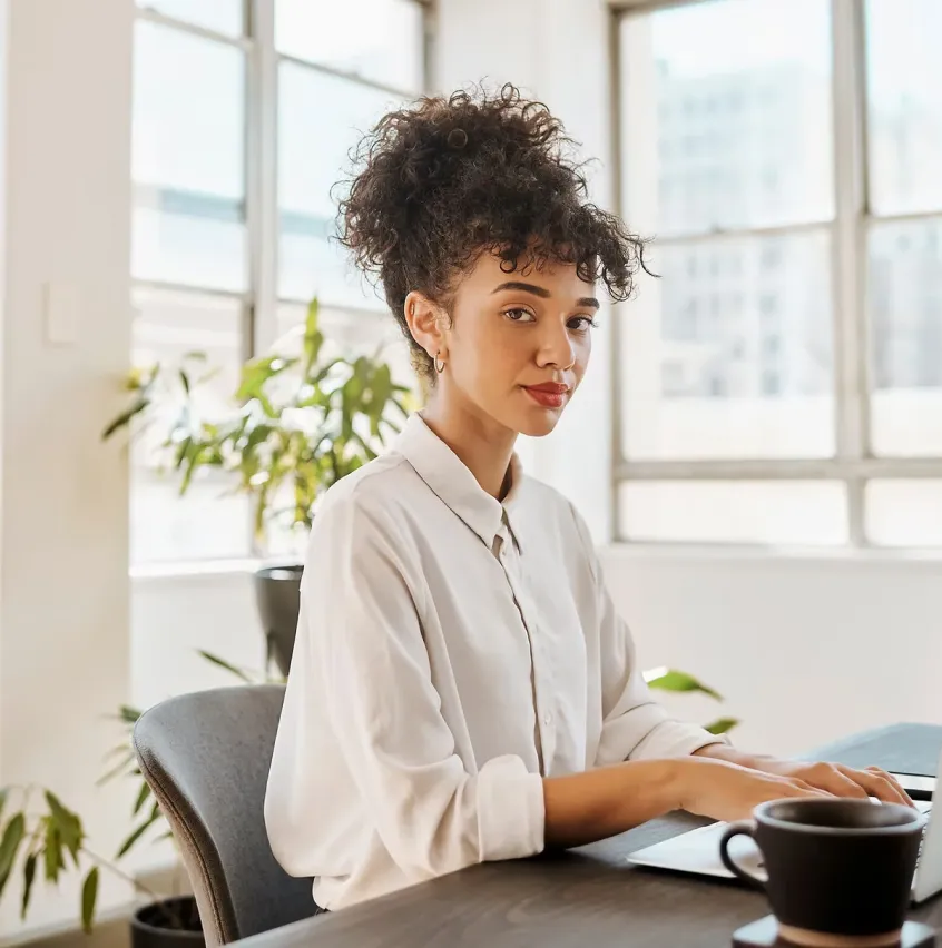 Jeune femme au bureau, profil réservée, regarde l'objectif